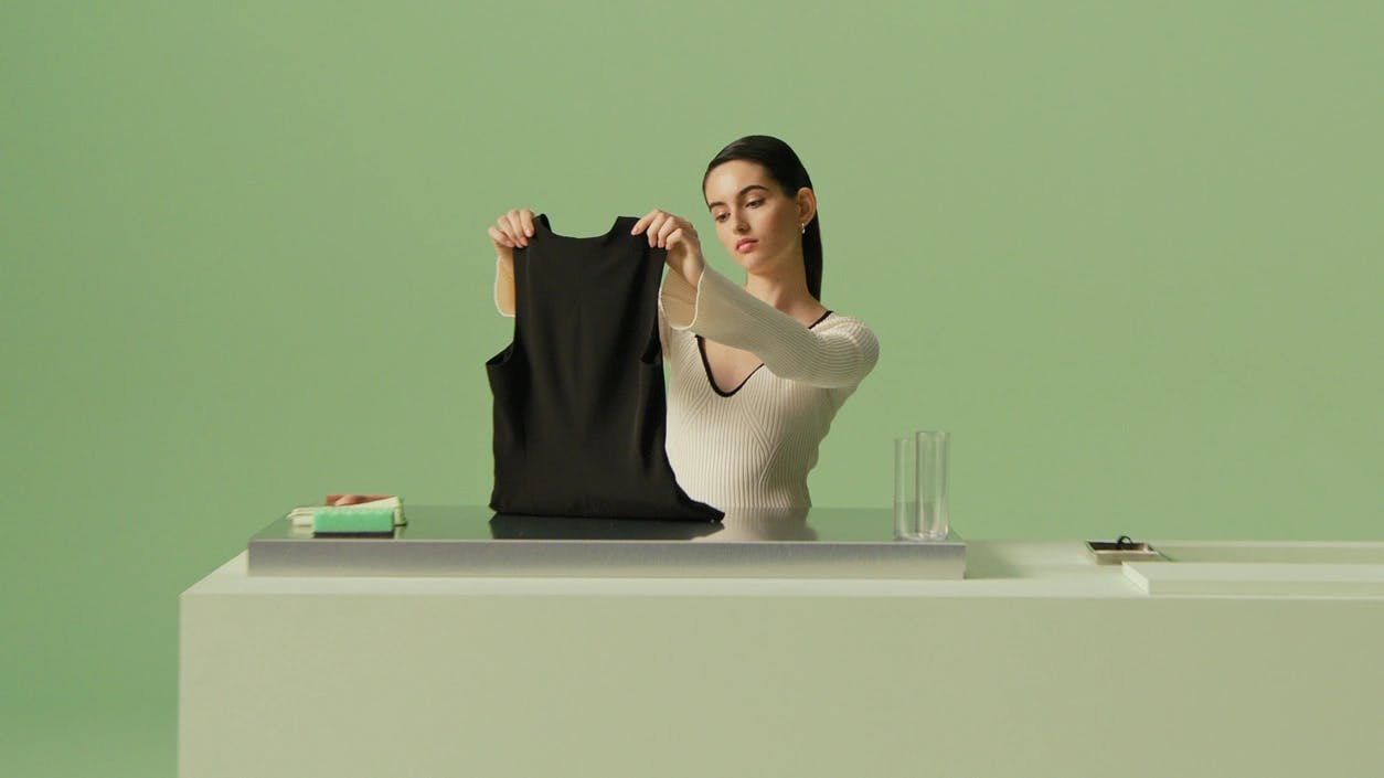 Girl holding a black shirt but a table with greenbackground
